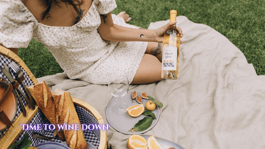 Young woman at a picnic on the ground with a wine bottle in hand